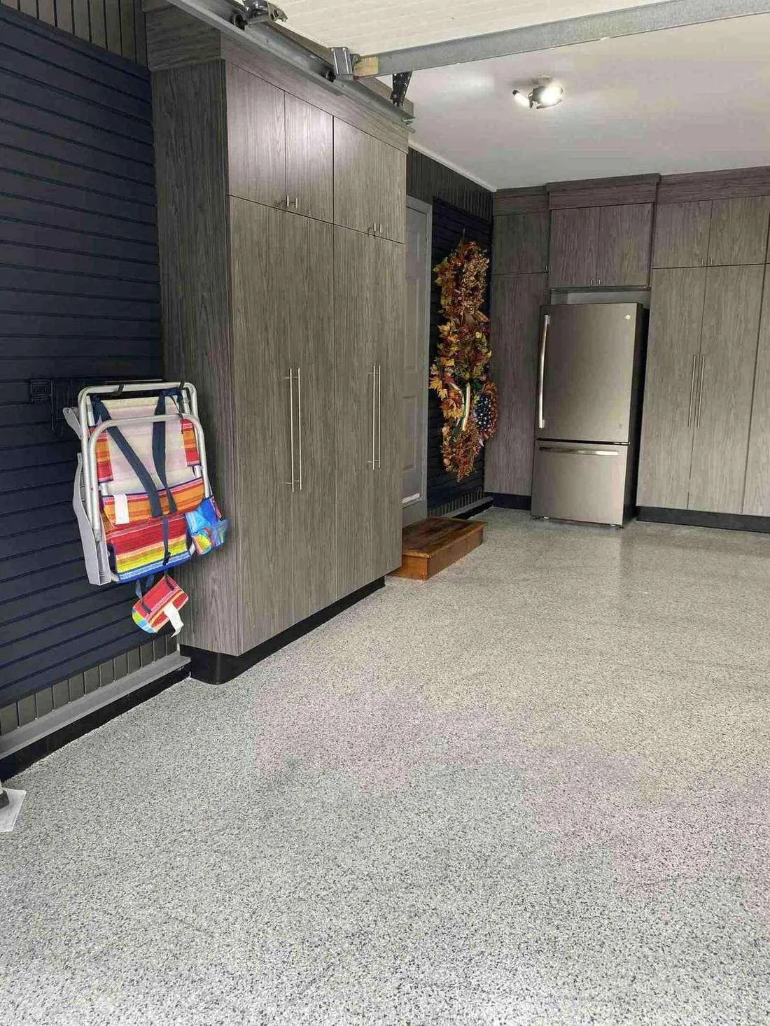 Garage with black slatwall and gray cabinets on an epoxy floor