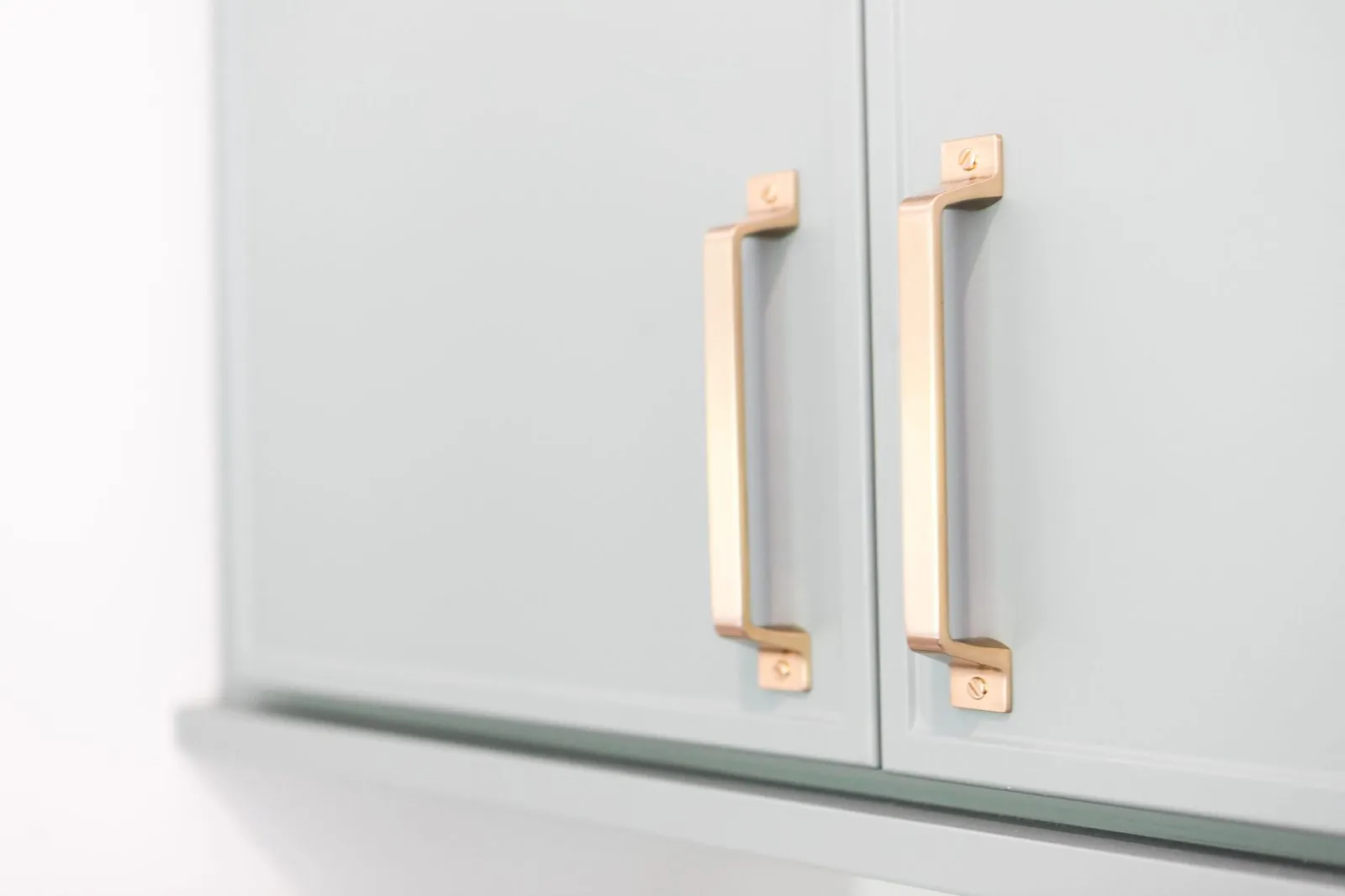Close-up of sage green cabinet doors with brass pulls