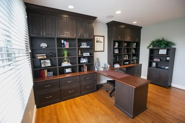 Dark wood home office with bookcases, upper cabinets and an L-shaped desk