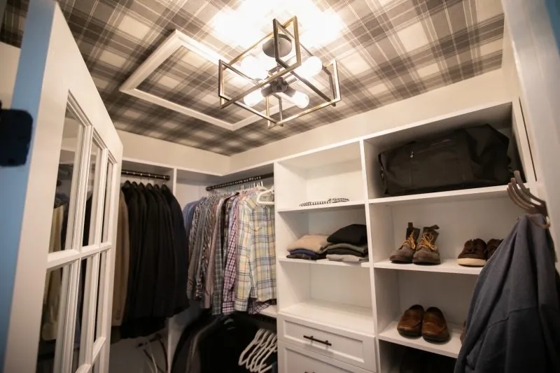 Walk-in closet with shelves, hanging and shoes under a plaid ceiling