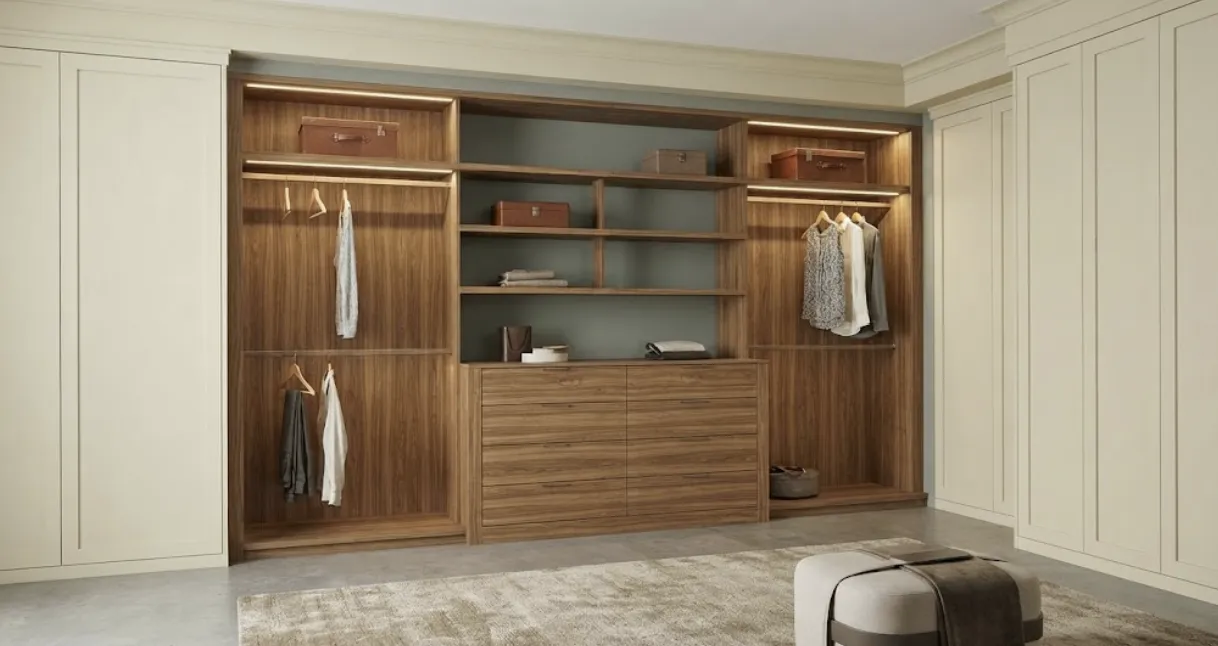 Walnut closet section with lit shelves, hanging rods and a drawer base between cream shaker wardrobe doors