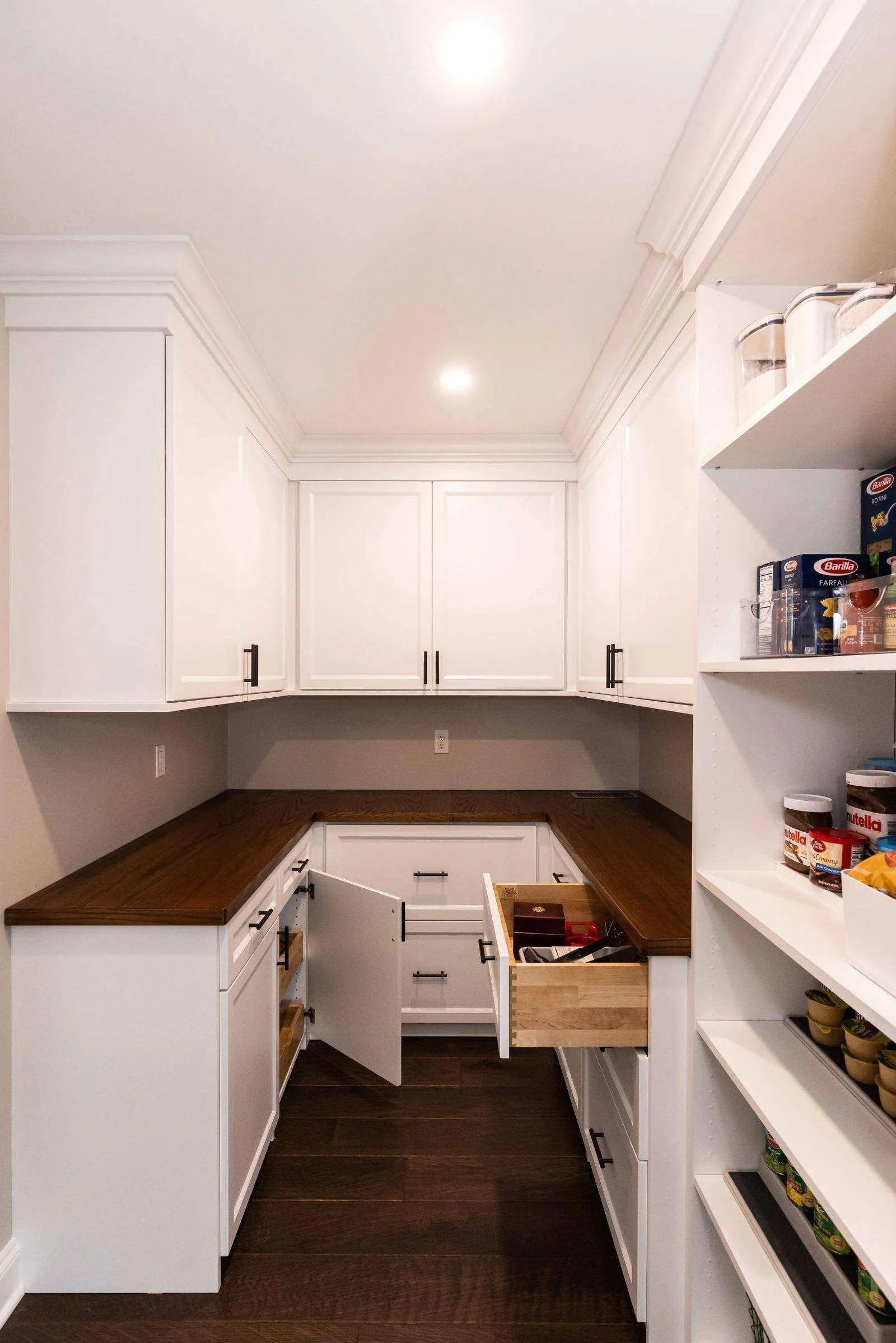 White U-shaped pantry with shelving, drawers and a wood counter